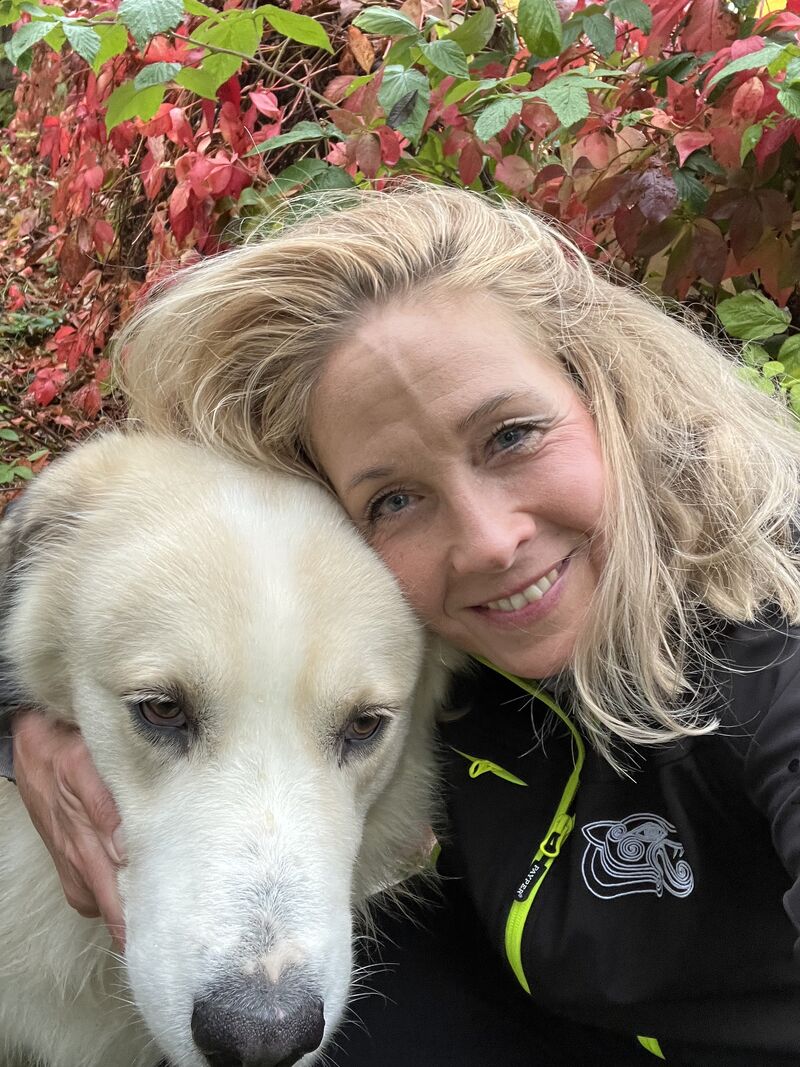 Silke Steinhauser with her dog in front of autumn leaves